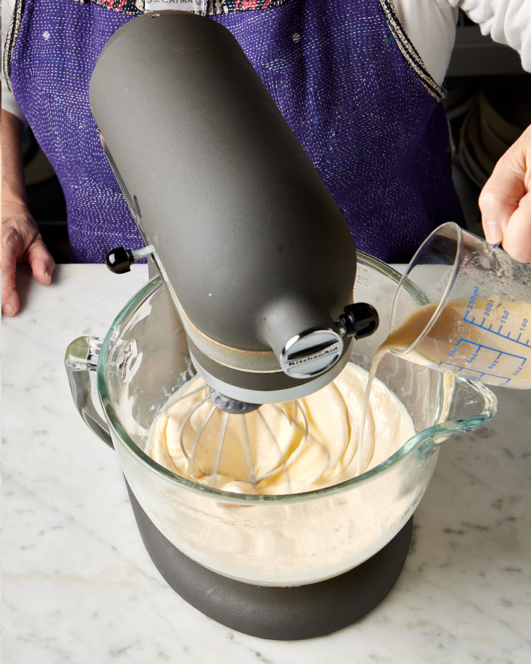 5. With the mixer running, slowly drizzle the milk mixture into the mixing bowl; the egg mixture will “loosen” in consistency. Using a silicone spatula, scrape down the bowl.
