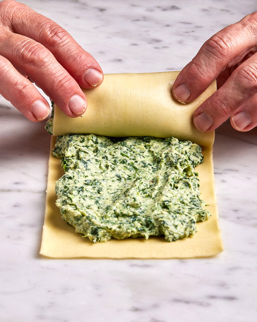 3. Starting with the edge closest to you, roll into a tight cylinder, using a finger to wipe any excess at the far end as you finish. Press to seal.