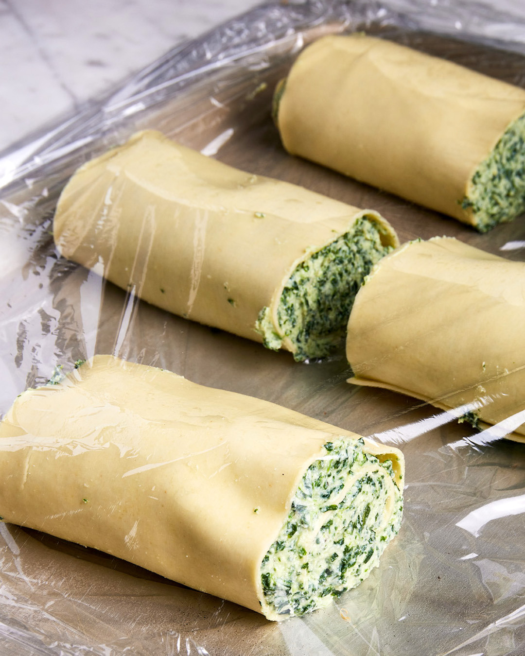 5. Place the rolls seam down on the prepared baking sheet. Cover with plastic wrap, then freeze until firm enough to easily cut, about 1½ hours.