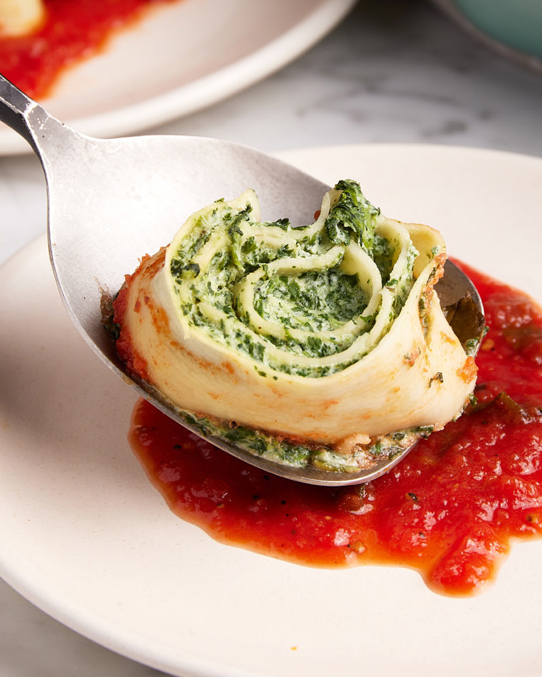 8. Spoon ¼ cup sauce onto each serving plate, then use a spatula to set a few rolls on top of the sauce on each. Sprinkle with additional Parmesan.
